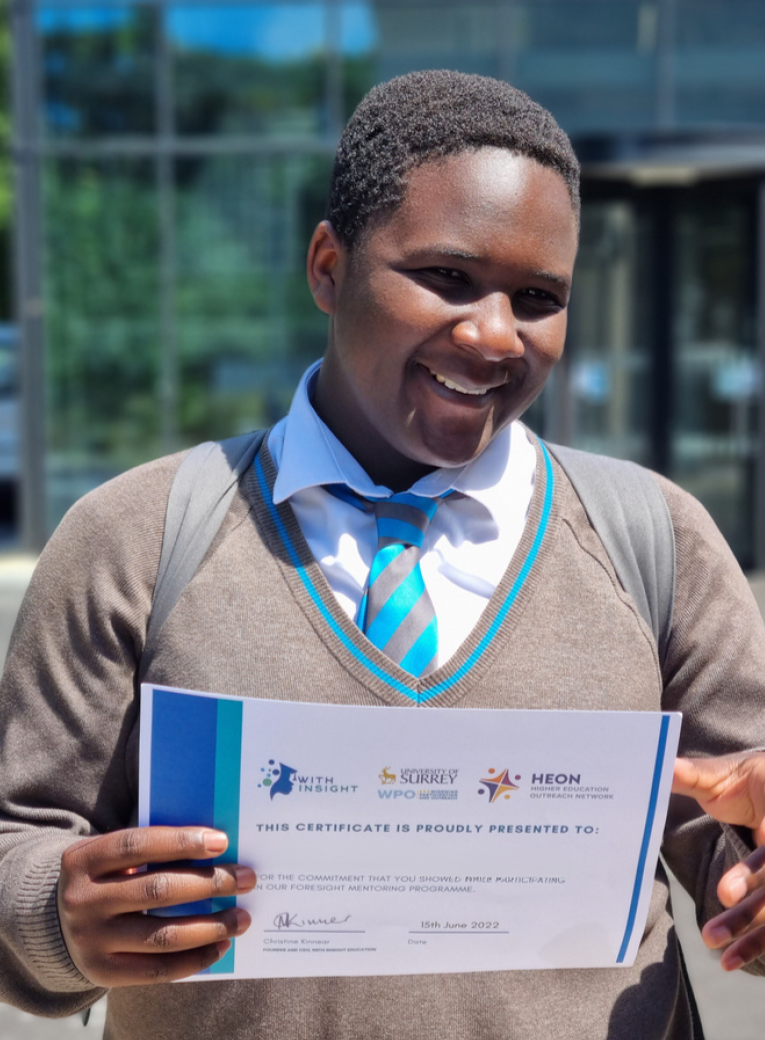 A smiling Black male WIE mentee holding his WIE certificate.