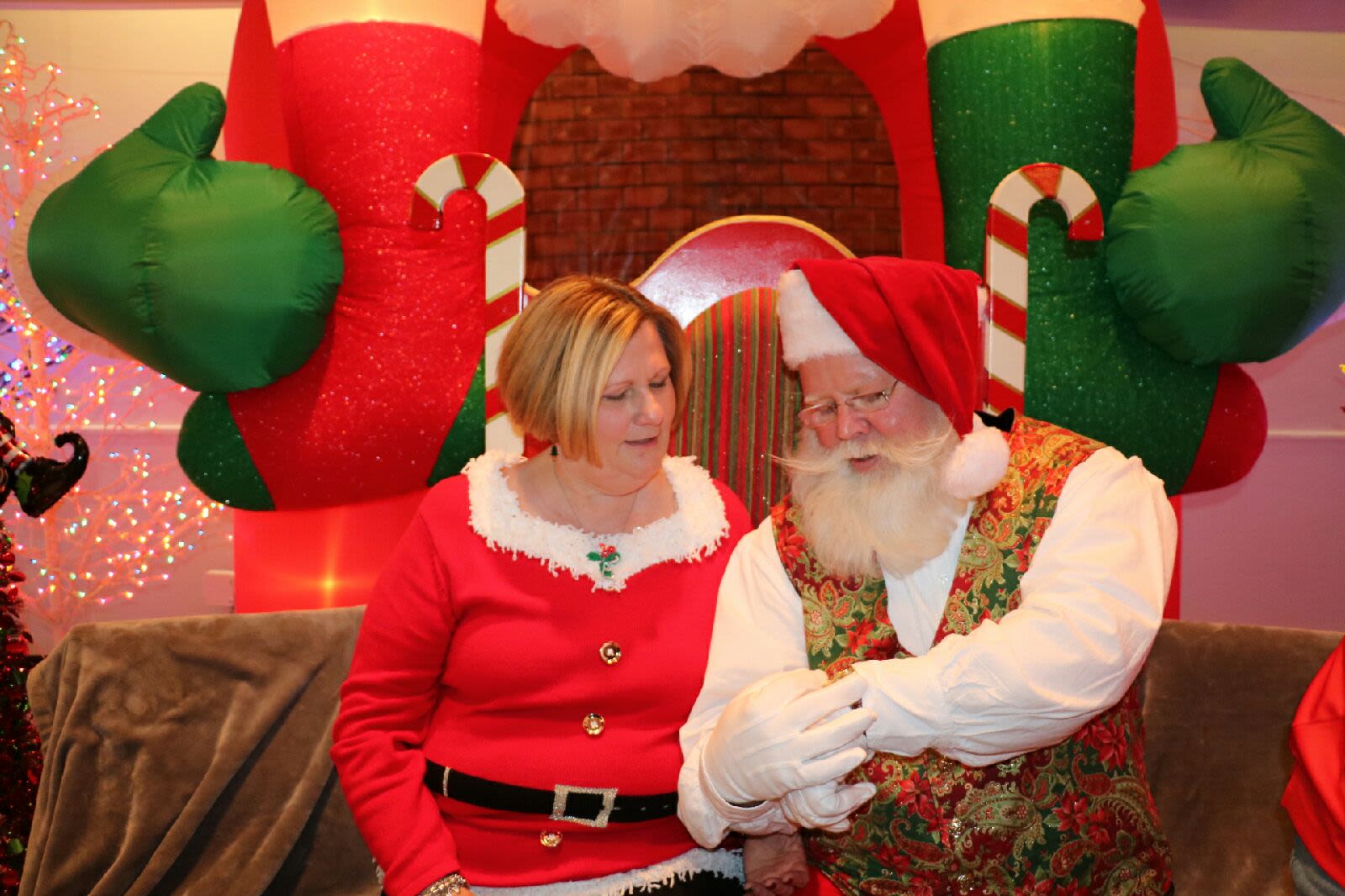 Debra Smith dressed as Miss Claus sitting next to Santa.
