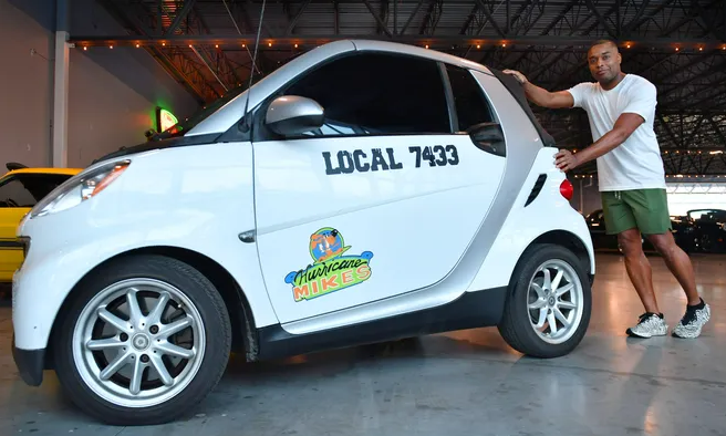 Javon Chapman standing at the back of the SmartCar he pushed for miles to raise money for The Special Olympics.